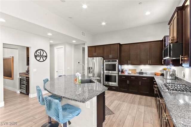 245 Hull St, Henderson, NV 89015 - kitchen with stainless steel appliances, beverage cooler, light wood-style flooring, light stone counters, and recessed lighting