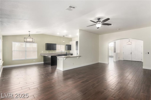 10058 Saint Augustine St, Las Vegas, NV 89183 - unfurnished living room featuring dark wood-style flooring, arched walkways, baseboards, ceiling fan, and vaulted ceiling