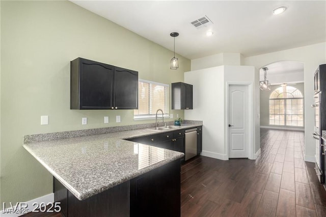 10058 Saint Augustine St, Las Vegas, NV 89183 - kitchen featuring a sink, stainless steel dishwasher, arched walkways, a peninsula, and dark wood-style floors