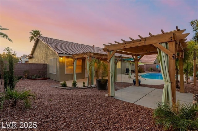 10058 Saint Augustine St, Las Vegas, NV 89183 - back of property featuring a pergola, a patio area, a fenced backyard, a tiled roof, and stucco siding