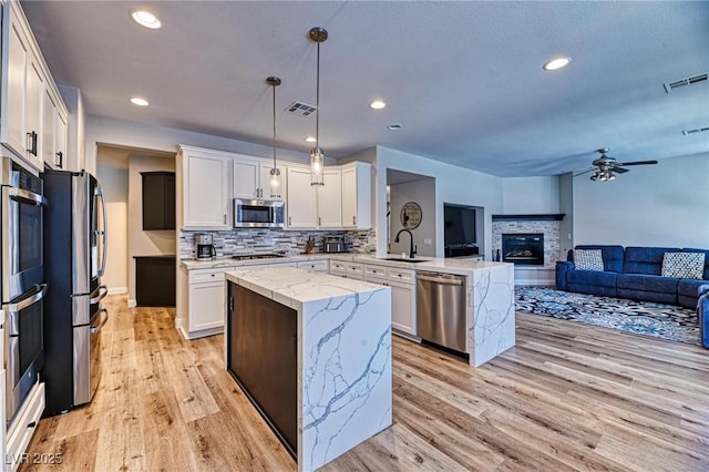 2285 Moresca Ave, Henderson, NV 89052 - kitchen with stainless steel appliances, a sink, open floor plan, a peninsula, and light wood-type flooring