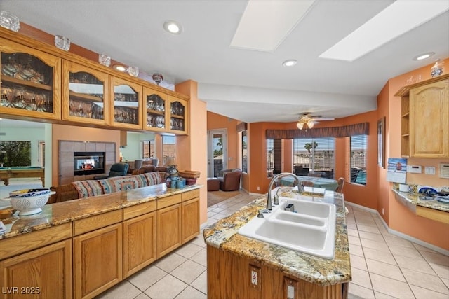 1105 Malachite Ct, Henderson, NV 89011 - kitchen with a sink, light tile patterned floors, a tile fireplace, glass insert cabinets, and recessed lighting