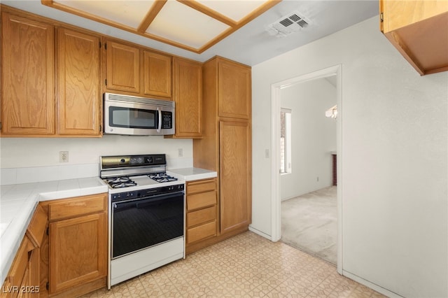 433 Old Palms Dr, Las Vegas, NV 89123 - kitchen with stainless steel microwave, gas range oven, light flooring, and tile counters