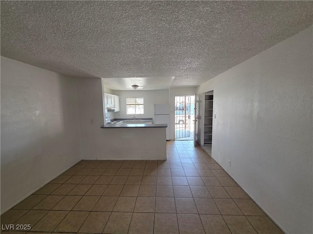5390 Swenson St Unit 27, Las Vegas, NV 89119 - unfurnished living room with a textured ceiling, light tile patterned floors, and a sink