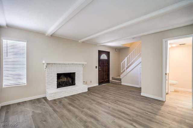 3683 Villa Knolls E Dr, Las Vegas, NV 89120 - unfurnished living room featuring beamed ceiling, wood finished floors, stairs, baseboards, and a fireplace