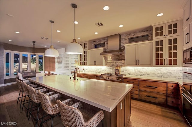 1972 Alcova Ridge Dr, Las Vegas, NV 89135 - kitchen with wall chimney range hood, a sink, a large island with sink, light wood-style floors, and recessed lighting