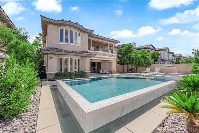 1972 Alcova Ridge Dr, Las Vegas, NV 89135 - rear view of house with a balcony, a tile roof, an outdoor pool, stucco siding, and a patio area