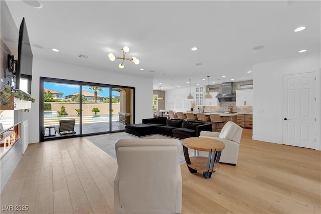 1972 Alcova Ridge Dr, Las Vegas, NV 89135 - living area featuring light wood-style flooring, recessed lighting, a lit fireplace, and a chandelier