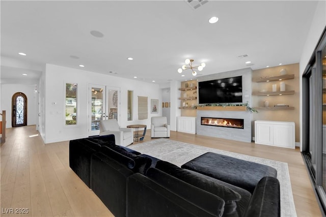 1972 Alcova Ridge Dr, Las Vegas, NV 89135 - living area featuring a glass covered fireplace, light wood finished floors, recessed lighting, built in shelves, and a chandelier