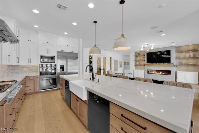 1972 Alcova Ridge Dr, Las Vegas, NV 89135 - kitchen with built in appliances, a sink, open floor plan, a lit fireplace, and light wood finished floors