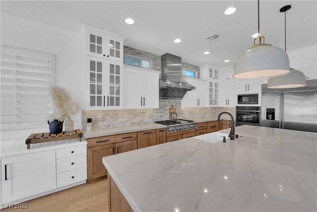 1972 Alcova Ridge Dr, Las Vegas, NV 89135 - kitchen featuring black appliances, wall chimney range hood, decorative backsplash, a sink, and light stone counters