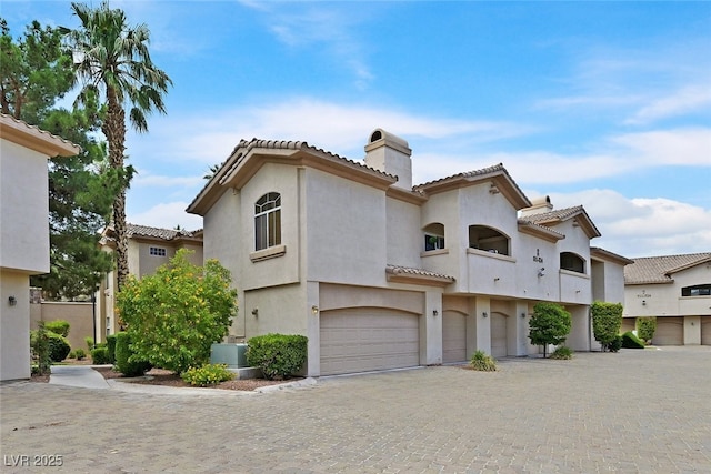 2050 W Warm Springs Rd Unit 823, Henderson, NV 89014 - view of front of home featuring a chimney, an attached garage, a tile roof, stucco siding, and driveway