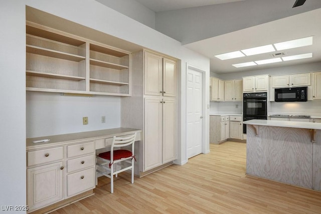 9524 Quail Ridge Dr, Las Vegas, NV 89134 - kitchen featuring black appliances, light wood finished floors, light countertops, a kitchen breakfast bar, and a skylight