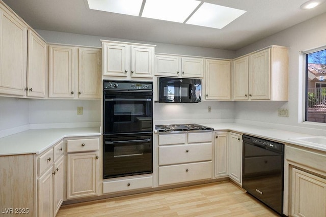 9524 Quail Ridge Dr, Las Vegas, NV 89134 - kitchen with black appliances, a skylight, light wood finished floors, and light brown cabinets