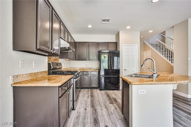 7083 Somera Way, Las Vegas, NV 89113 - kitchen featuring freestanding refrigerator, stainless steel range with gas cooktop, a sink, under cabinet range hood, and light wood-style flooring
