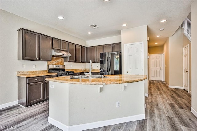 7083 Somera Way, Las Vegas, NV 89113 - kitchen with stainless steel gas stove, freestanding refrigerator, under cabinet range hood, a sink, and dark brown cabinetry