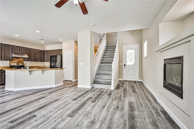 7083 Somera Way, Las Vegas, NV 89113 - kitchen featuring stainless steel gas range oven, black fridge, under cabinet range hood, light wood-style flooring, and ceiling fan