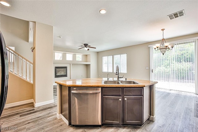 7083 Somera Way, Las Vegas, NV 89113 - kitchen with stainless steel dishwasher, a sink, dark brown cabinetry, light wood-type flooring, and light countertops