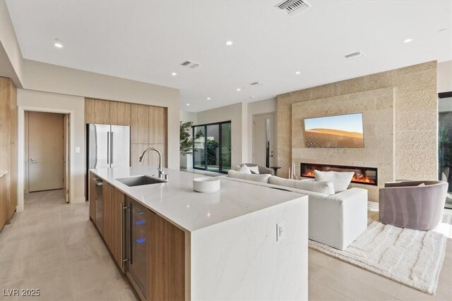 40 Heron Harbour Dr, Henderson, NV 89011 - kitchen with modern cabinets, a sink, fridge, a large island with sink, and a fireplace