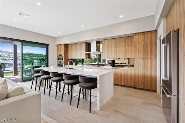40 Heron Harbour Dr, Henderson, NV 89011 - kitchen with appliances with stainless steel finishes, modern cabinets, wall chimney exhaust hood, a breakfast bar, and recessed lighting