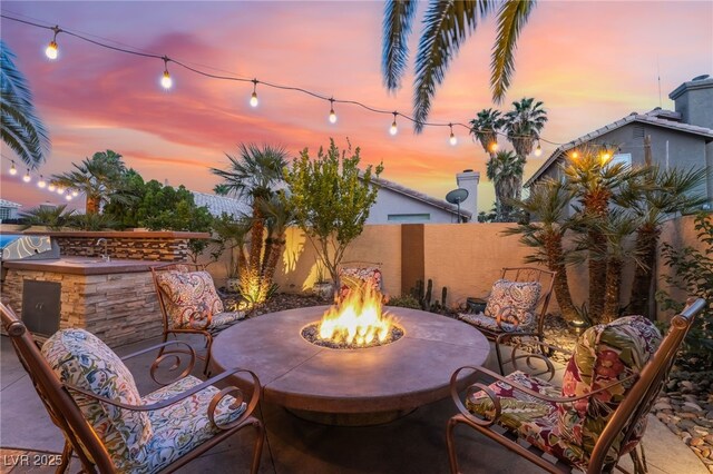 5779 Baffy Cir, Las Vegas, NV 89142 - patio terrace at dusk with an outdoor fire pit, a patio, a fenced backyard, and a grill