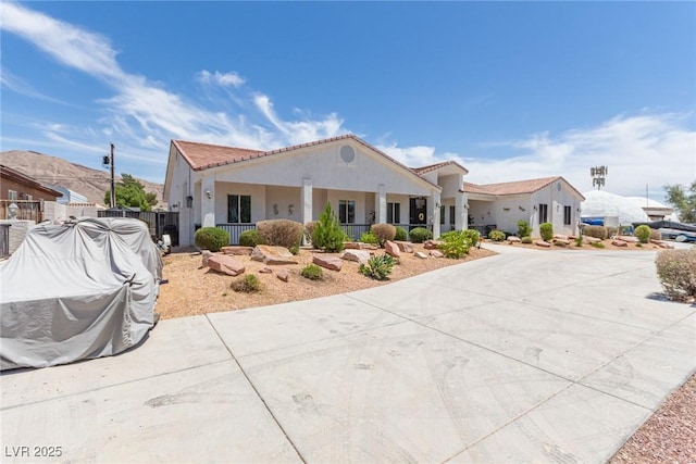 60 N Fogg St, Las Vegas, NV 89110 - view of front of home with stucco siding, a porch, a tile roof, and curved driveway
