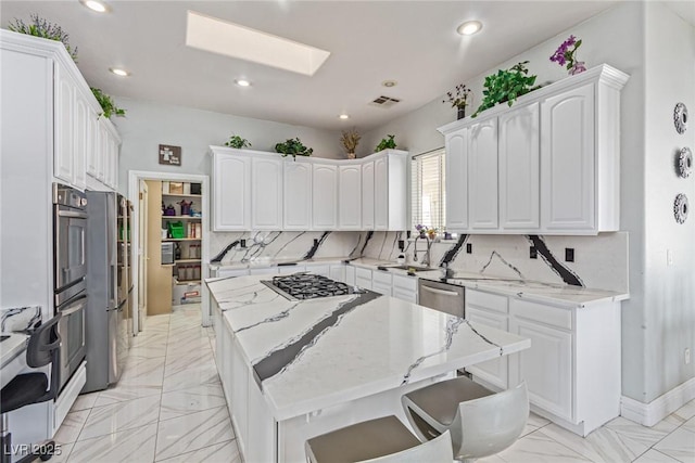 60 N Fogg St, Las Vegas, NV 89110 - kitchen featuring appliances with stainless steel finishes, white cabinets, light marble finish flooring, a kitchen island, and recessed lighting