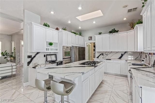 60 N Fogg St, Las Vegas, NV 89110 - kitchen featuring stainless steel appliances, a center island, backsplash, a skylight, and light marble finish floors