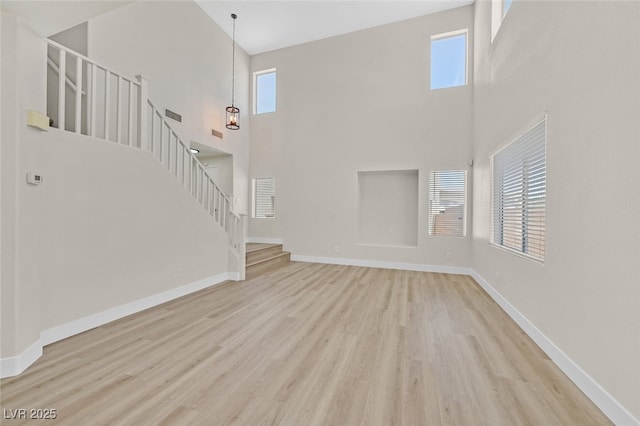 4132 Joyous St, North Las Vegas, NV 89032 - unfurnished living room featuring stairs, a high ceiling, wood finished floors, and baseboards