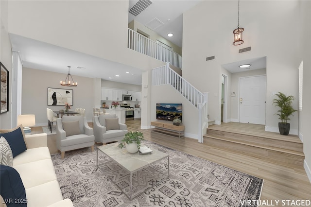 4132 Joyous St, North Las Vegas, NV 89032 - living area featuring a chandelier, a towering ceiling, stairs, light wood-style floors, and baseboards