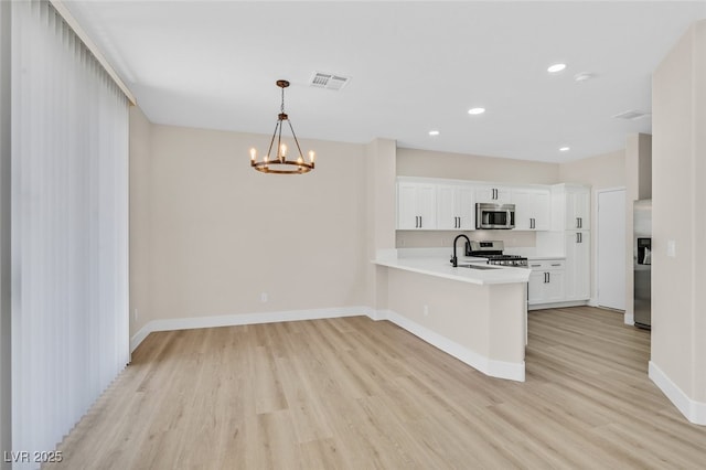 4132 Joyous St, North Las Vegas, NV 89032 - kitchen with stainless steel appliances, a chandelier, light wood-style flooring, a peninsula, and recessed lighting