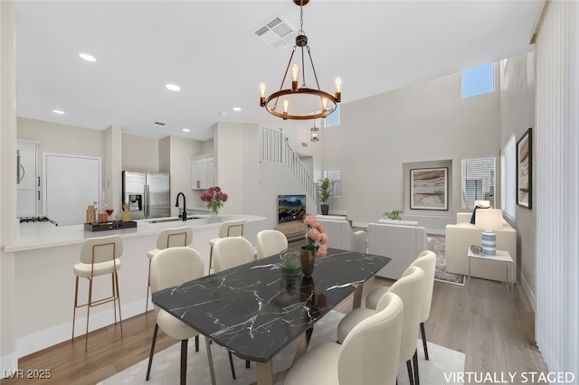 4132 Joyous St, North Las Vegas, NV 89032 - dining space featuring light wood-type flooring, a chandelier, baseboards, recessed lighting, and stairway
