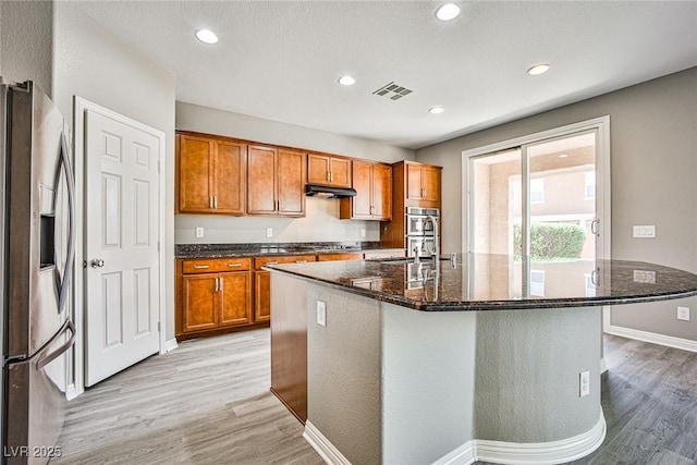 9271 Martel Ave, Las Vegas, NV 89148 - kitchen featuring stainless steel refrigerator with ice dispenser, light wood-style floors, brown cabinetry, dark stone counters, and recessed lighting