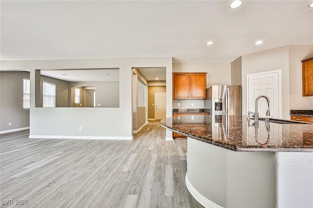 9271 Martel Ave, Las Vegas, NV 89148 - kitchen featuring stainless steel fridge, a sink, light wood finished floors, brown cabinets, and baseboards