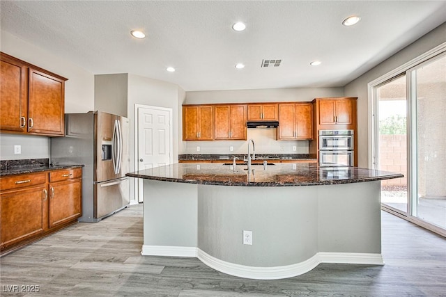 9271 Martel Ave, Las Vegas, NV 89148 - kitchen featuring appliances with stainless steel finishes, brown cabinets, light wood-style floors, under cabinet range hood, and a sink
