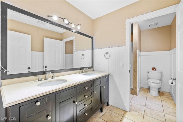 7545 Constantinople Ave, Las Vegas, NV 89129 - full bath with wainscoting, double vanity, tile patterned flooring, and toilet