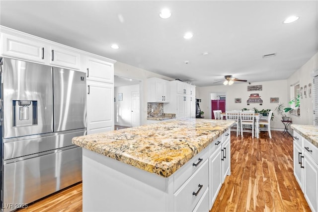 7545 Constantinople Ave, Las Vegas, NV 89129 - kitchen with stainless steel fridge with ice dispenser, a ceiling fan, white cabinets, light stone countertops, and light wood-style flooring
