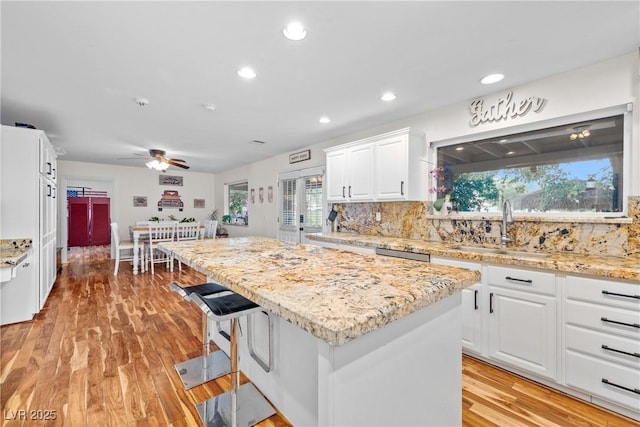 7545 Constantinople Ave, Las Vegas, NV 89129 - kitchen featuring a sink, a kitchen island, white cabinets, tasteful backsplash, and healthy amount of natural light