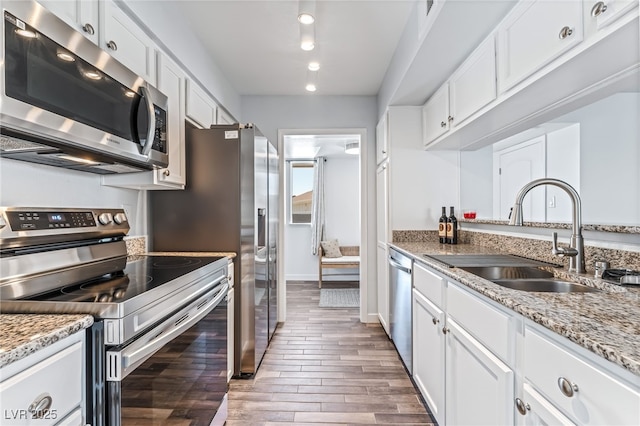 753 Oakmont Ave Unit 802, Las Vegas, NV 89109 - kitchen with appliances with stainless steel finishes, a sink, wood finished floors, white cabinets, and light stone countertops