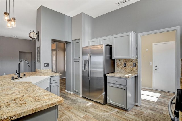 3112 Haddon Dr, Las Vegas, NV 89134 - kitchen with stainless steel fridge, range, light wood-type flooring, tasteful backsplash, and gray cabinets