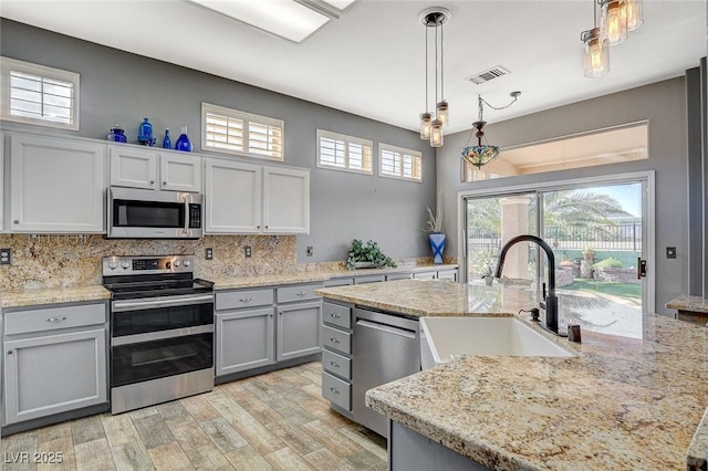 3112 Haddon Dr, Las Vegas, NV 89134 - kitchen with stainless steel appliances, gray cabinetry, light wood-style floors, and backsplash