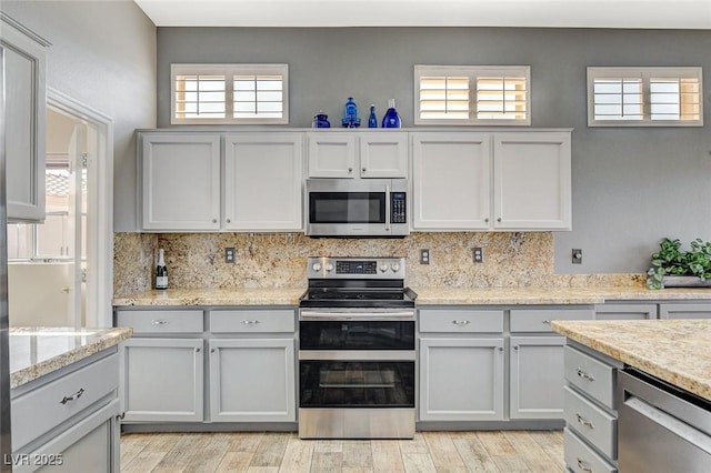 3112 Haddon Dr, Las Vegas, NV 89134 - kitchen featuring stainless steel appliances, backsplash, light wood-style floors, and light stone counters