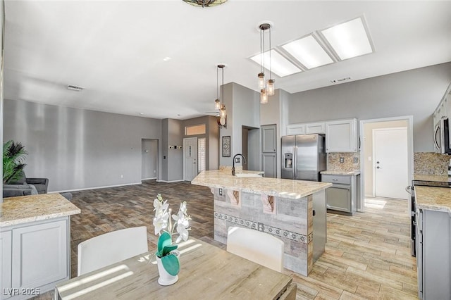 3112 Haddon Dr, Las Vegas, NV 89134 - kitchen with appliances with stainless steel finishes, light wood-type flooring, decorative backsplash, light stone countertops, and open floor plan