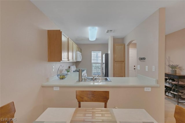6217 Lapilli Ave, Las Vegas, NV 89139 - kitchen featuring freestanding refrigerator, arched walkways, white microwave, a peninsula, and light countertops