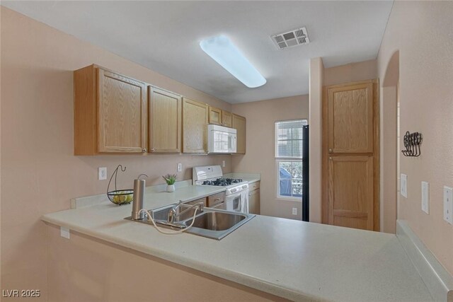 6217 Lapilli Ave, Las Vegas, NV 89139 - kitchen with white appliances, a sink, light brown cabinetry, light countertops, and a peninsula