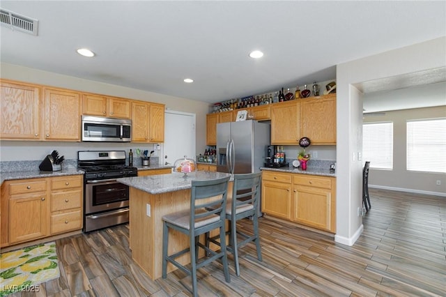 9039 Alex Creek Ave, Las Vegas, NV 89149 - kitchen with appliances with stainless steel finishes, a center island, wood finished floors, light stone countertops, and recessed lighting