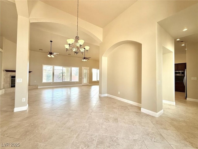 5451 Fernwood Ct, Pahrump, NV 89061 - spare room with high vaulted ceiling, a chandelier, a ceiling fan, baseboards, and a premium fireplace