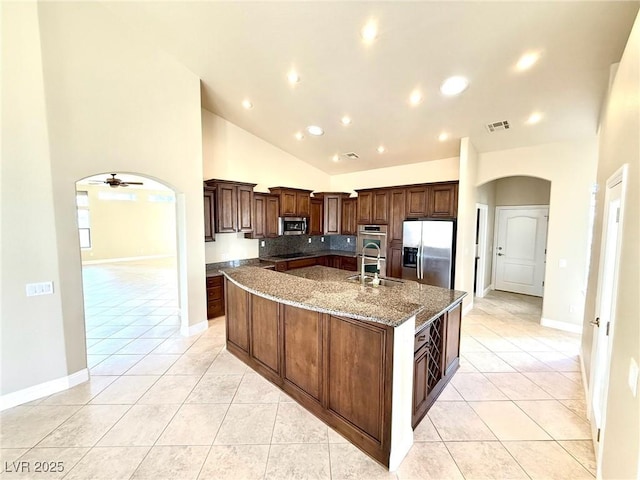 5451 Fernwood Ct, Pahrump, NV 89061 - kitchen with stainless steel appliances, arched walkways, a sink, light tile patterned floors, and a large island with sink