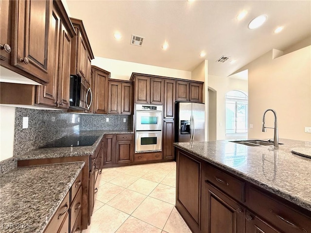 5451 Fernwood Ct, Pahrump, NV 89061 - kitchen featuring a sink, appliances with stainless steel finishes, backsplash, arched walkways, and dark stone countertops
