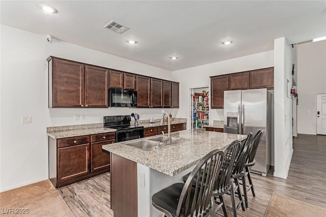 3821 E Summit Ave, Pahrump, NV 89061 - kitchen with black appliances, a sink, a kitchen bar, dark brown cabinetry, and an island with sink